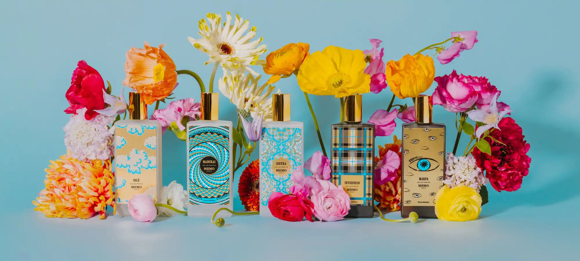 Artistic perfume bottles amidst colorful flowers.