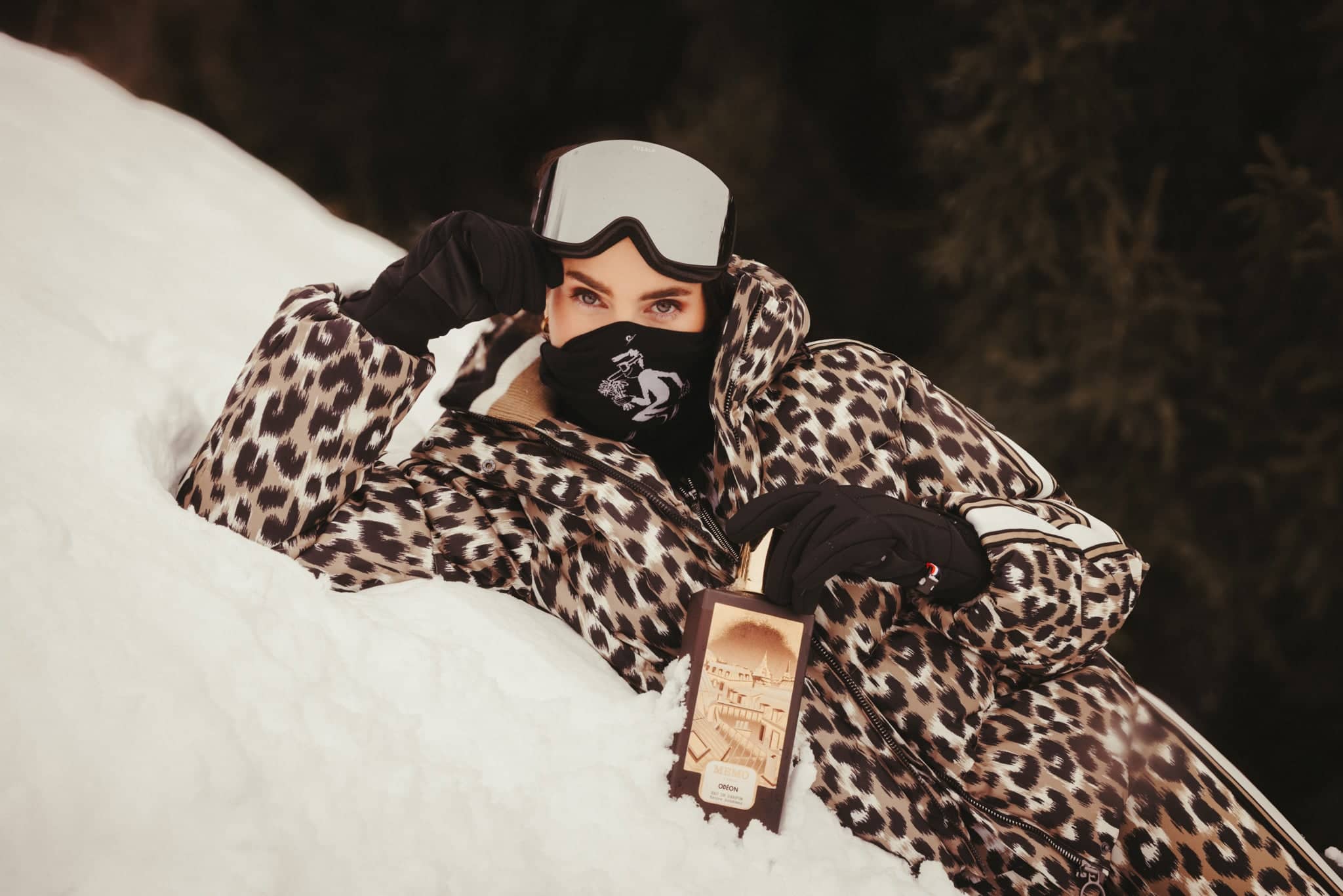 A leopard-print puffer jacket with white trim on the sleeves and hood, worn by a person in snowy terrain.